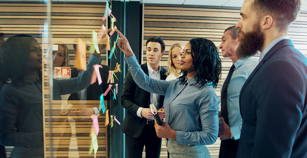 Five people talking around a board with sticky notes on