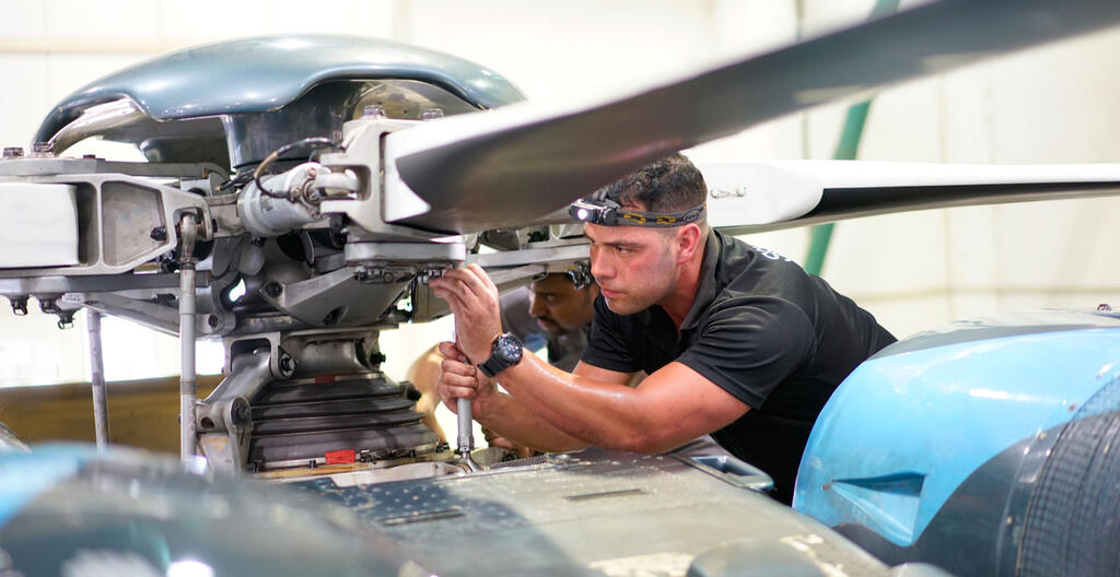 An individual working on a helicopter rotorhead