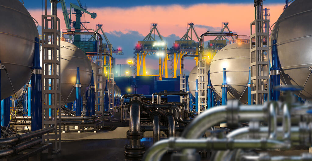 Liquefied natural gas terminal with spherical storage tanks, pipelines and cranes at port during sunset operations. LNG storage, transport, energy industry
