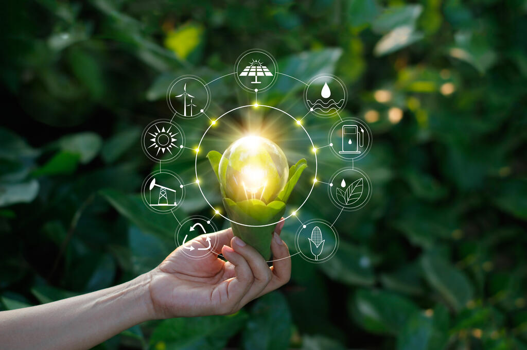A hand holding leaves encasing a lightbulb, with CGI icons of various energy sources overlaid, symbolizing a push to renewable energy.