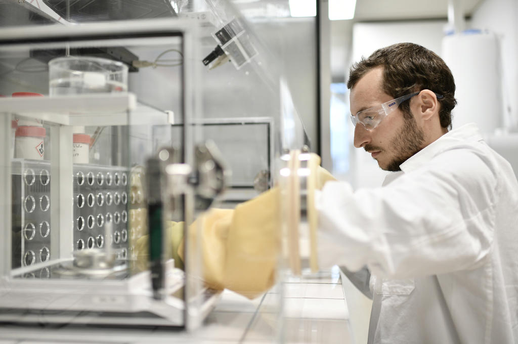 A man in labwear working in a fume cupboard