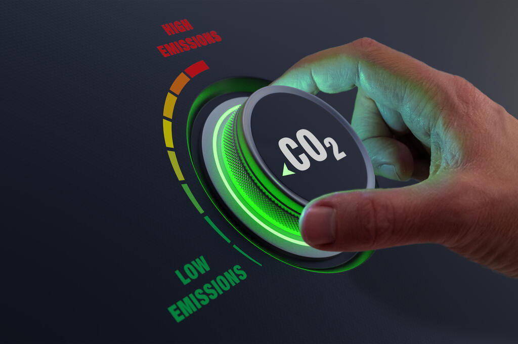 A dial with CO2 written on it, turned to a low setting, symbolizing net zero carbon emissions