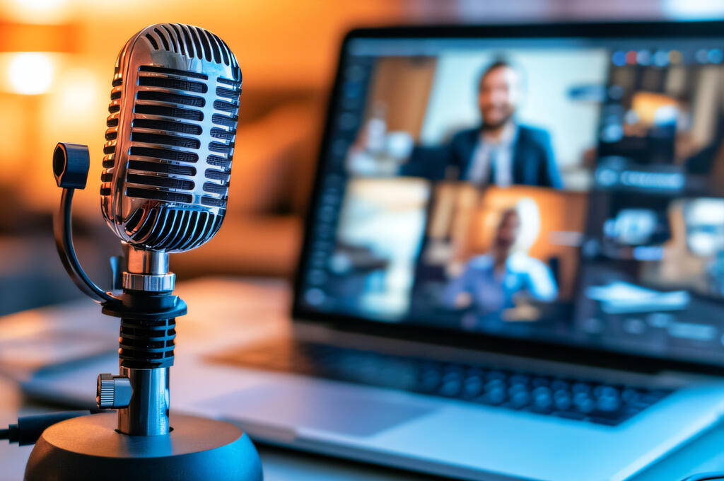 A desk featuring a microphone next to a laptop, representing our podcasts and webinar series