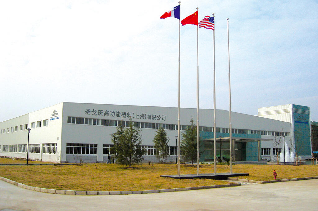 A prominent warehouse & manufacturing building featuring several flags, representing various nations, fluttering in the breeze.