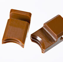 Two brown custom-made polyimide components placed on a white surface, designed to meet customer requirements for mechanical strength.
