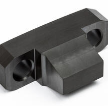 A custom-designed and manufactured black polyimide block featuring two openings, engineered for high-temperature performance.
