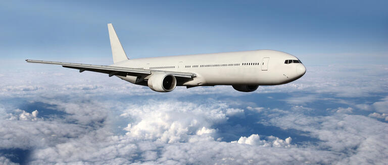 A plane flying above some clouds in blue skies