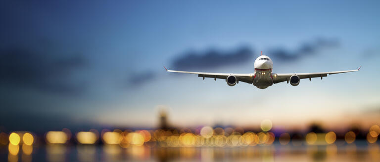 A plane in flight, on a cityscape background