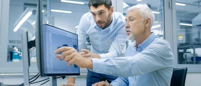 Two individuals discussing sales data at a monitor