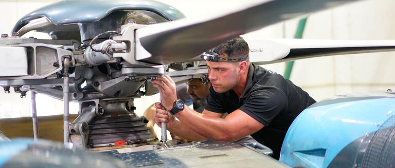 An individual working on a helicopter rotorhead