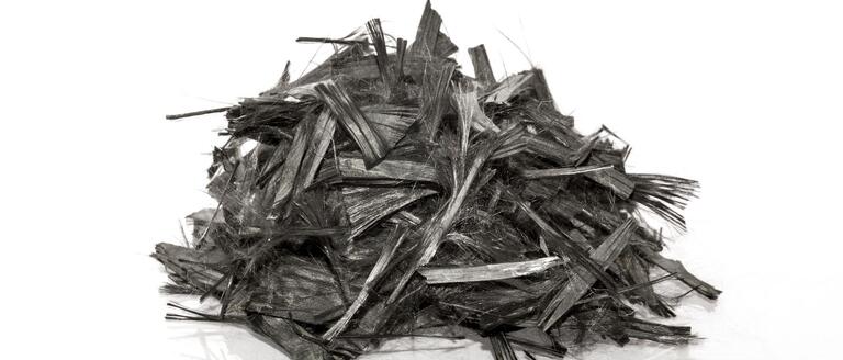  Shredded carbon fibers arranged on a white surface, highlighting their unique composition and texture.